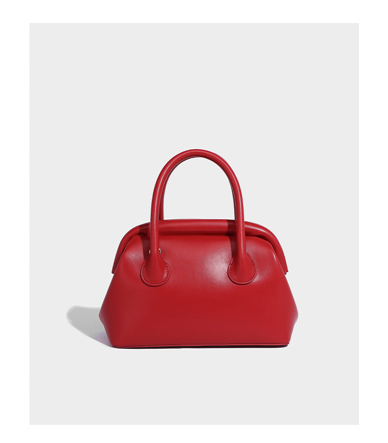 Small structured shell top-handle bag in red with heart charm and braided cord detail, smooth leather-look finish, detail