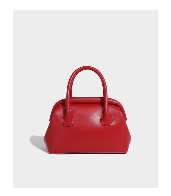 Small structured shell top-handle bag in red with heart charm and braided cord detail, smooth leather-look finish, detail