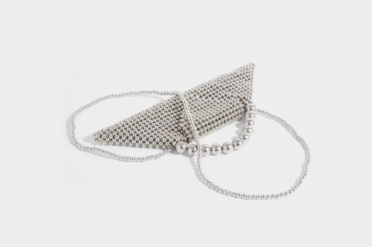 Small structured triangle clutch bag covered in glossy pearl beads with an arched pearl top handle and silver snap closure