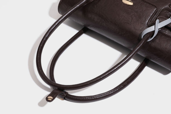 Structured glossy leather-look satchel bag with flap closure, gold-tone buckle accents, double top handles, detachable