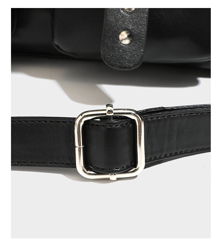 Black leather-look tote bag with silver pyramid studs on handles and front panel, multiple flap and zip exterior pockets