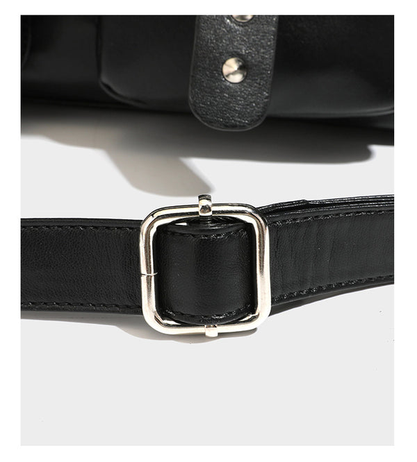 Black leather-look tote bag with silver pyramid studs on handles and front panel, multiple flap and zip exterior pockets