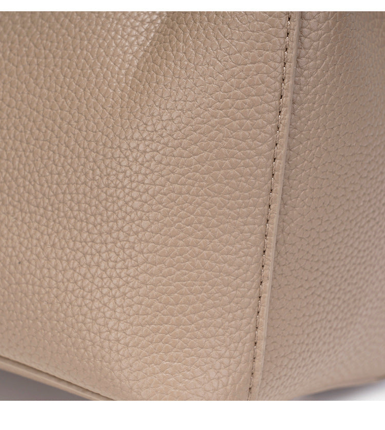 Compact structured bucket bag in pebbled leather-look finish with silver turn-lock front clasp, dual top handles, detachable