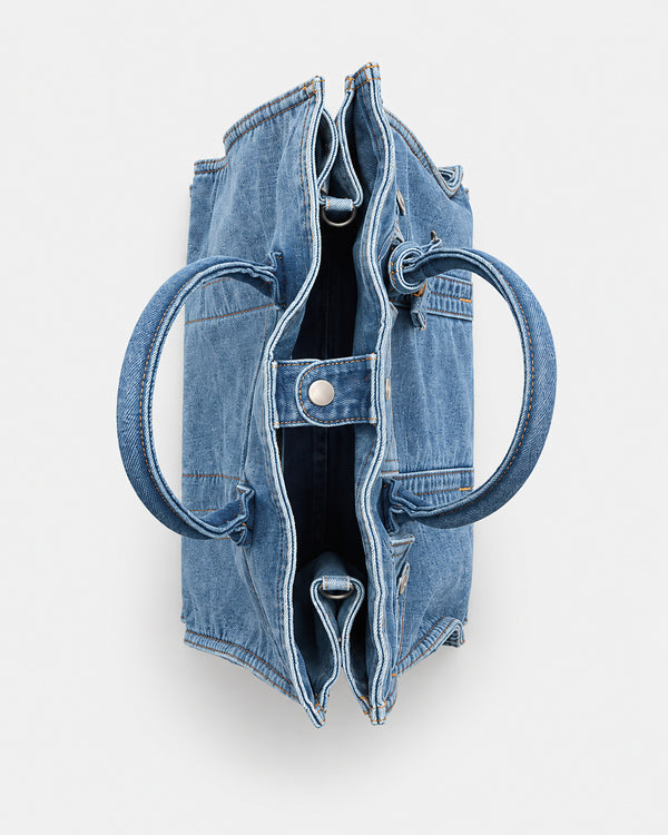Large washed denim patchwork tote bag with snap-flap front pockets, rolled handles, and detachable shoulder strap, detail