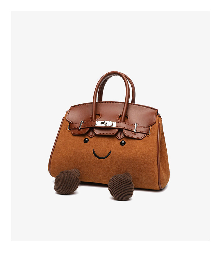 Small structured trapezoid satchel bag with smiling face motif, pom-pom accents, brown leather-look trim, silver-tone, detail