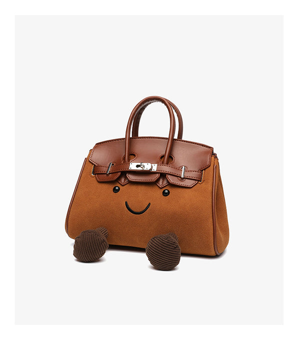 Small structured trapezoid satchel bag with smiling face motif, pom-pom accents, brown leather-look trim, silver-tone, detail