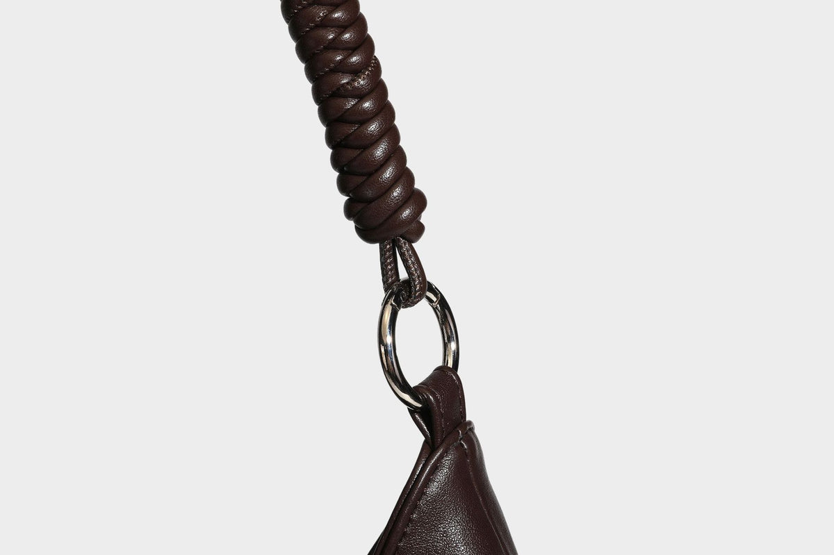 Large slouchy hobo shoulder bag with braided top handle, smooth glossy leather-look finish, and silver-tone ring hardware