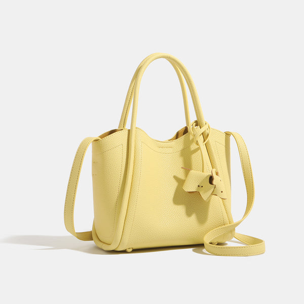 Small structured pebbled leather-look bucket tote bag with bow charm tie closure and gold-tone hardware, detail view 3