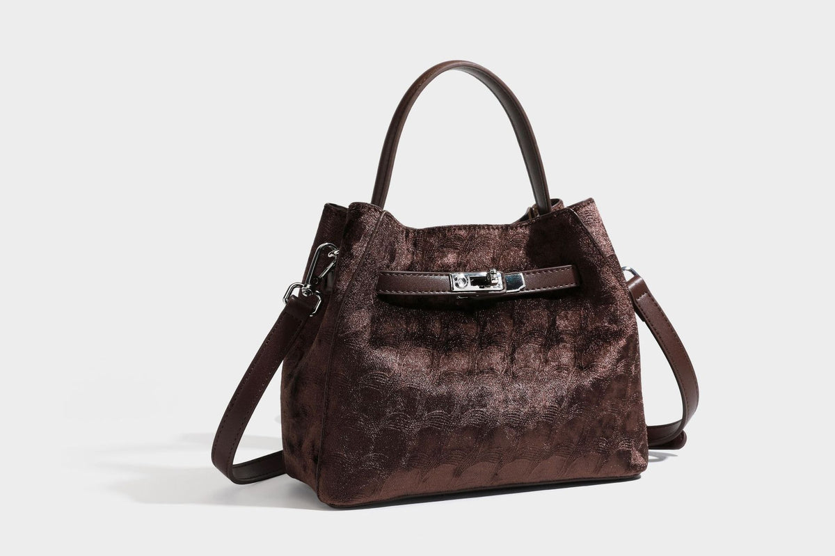 Small structured bucket satchel in embossed velvet-texture fabric with silver turn-lock hardware, rounded top handle, and