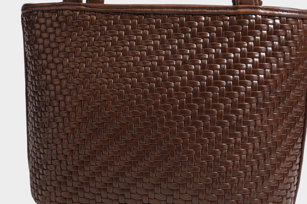 Strukturierte Tote Bag mit gewebter Oberfläche in Braun, goldfarbenen Metalldetails, seilumwickelten Tragegriffen, einer kleinen Fronttasche und weiteren Details