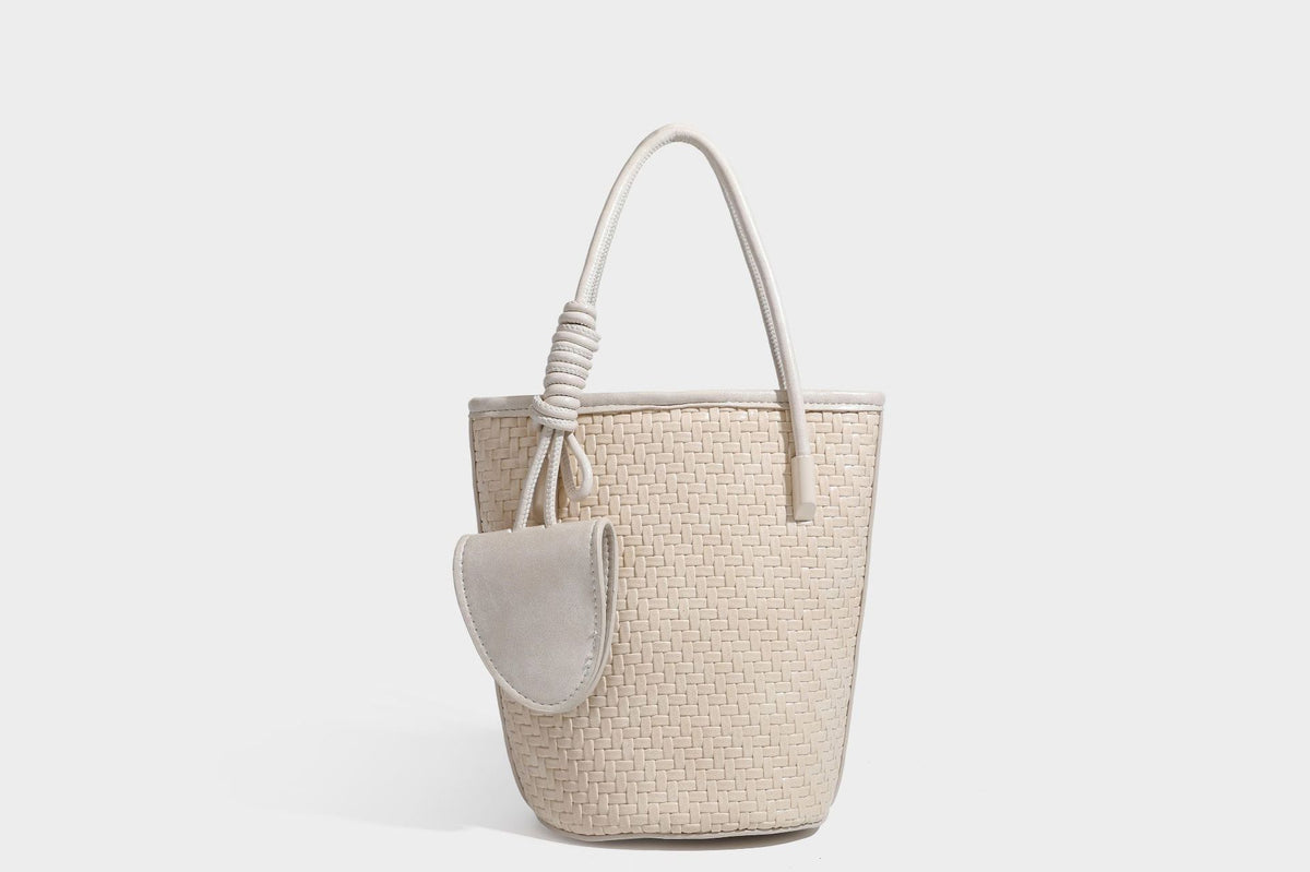 Structured woven-texture leather-look bucket bag in brown with knotted top handles, small front flap pouch, and adjustable