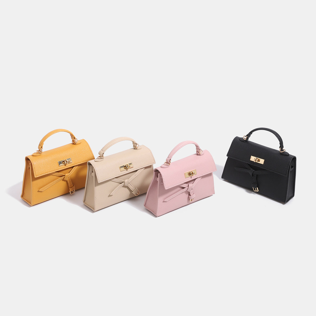 Structured trapezoid leather-look handbag with bow front detail, gold-tone rectangular turn-lock, short top handle, and