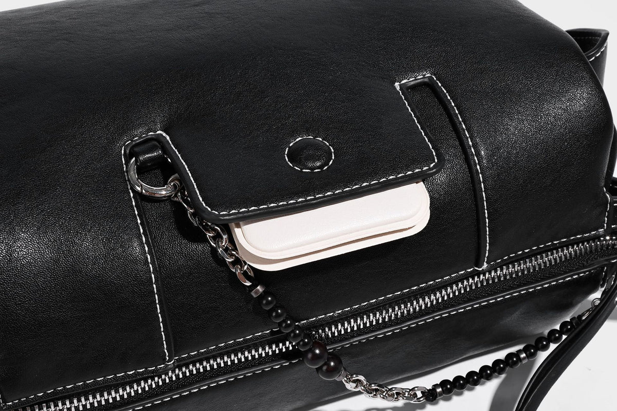 Small slouchy moto-style crossbody bag in smooth matte leather-look finish with white contrast stitching, silver-tone, detail