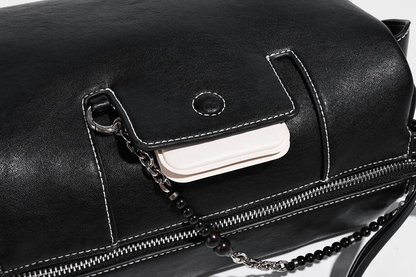 Small slouchy moto-style crossbody bag in smooth matte leather-look finish with white contrast stitching, silver-tone, detail