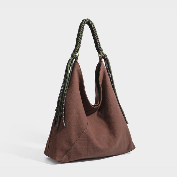 Soft slouchy cream canvas shoulder tote with braided brown and green cord handle, gold-tone ring hardware, and tassel trim