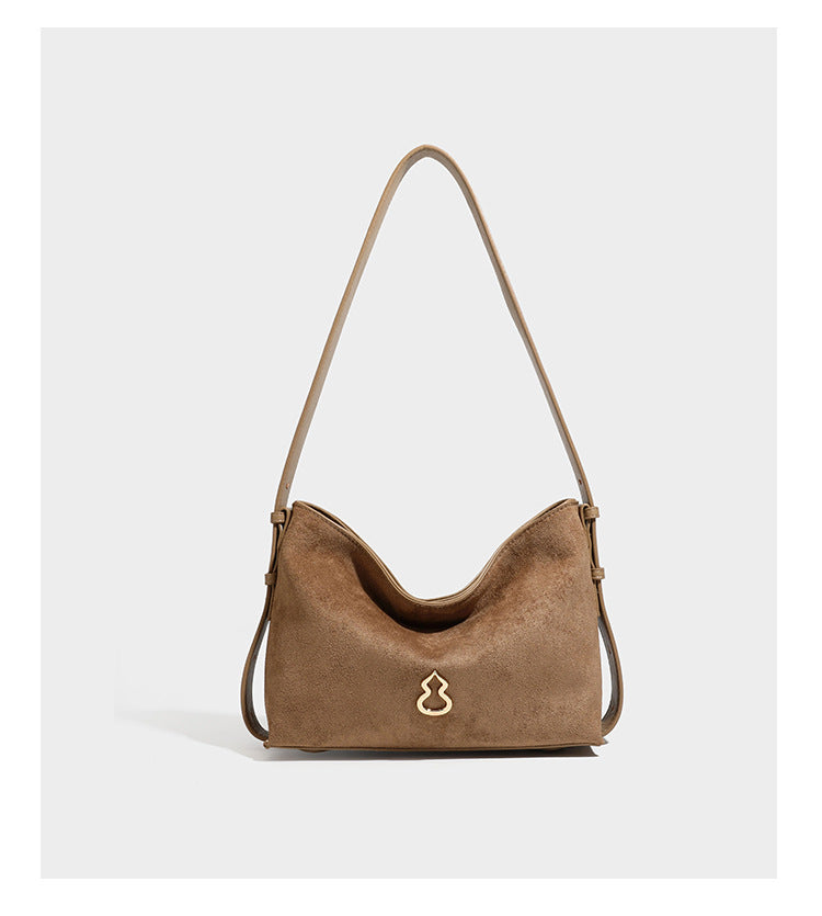 Slouchy suede-finish brown shoulder bag with long single strap and small gold-tone logo emblem on front, detail view 17