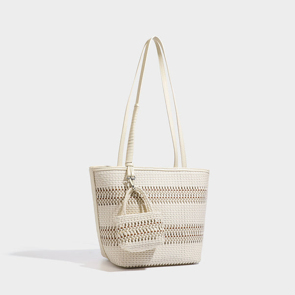 Large structured woven tote bag with striped basket-weave finish, long shoulder straps, and detachable mini pouch charm