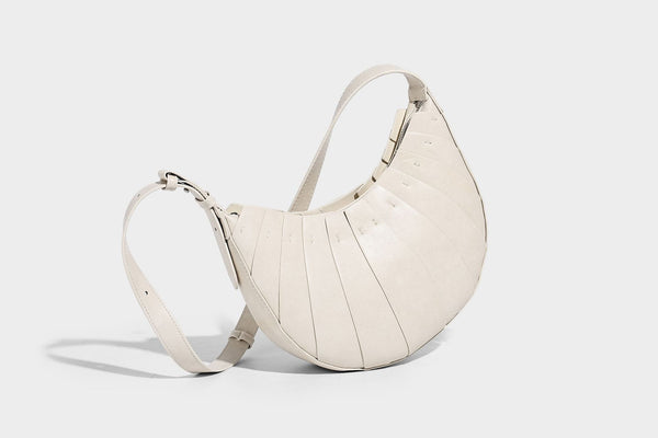 Crescent half-moon shoulder bag with vertical panel seaming, matte-satin leather-look finish, and adjustable gold-tone