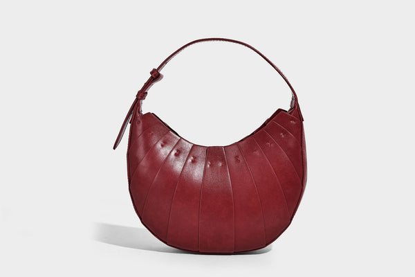 Crescent half-moon shoulder bag with vertical panel seaming, matte-satin leather-look finish, and adjustable gold-tone