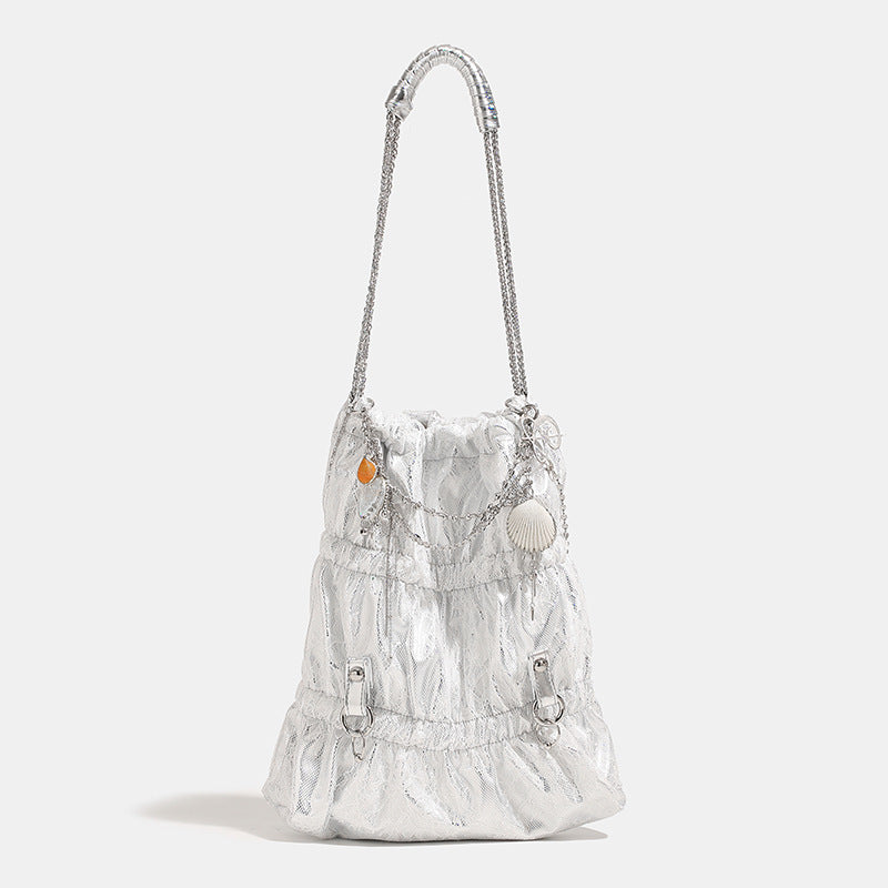 Slouchy lace-texture bucket bag with silver-tone chain strap, draped chain hardware, and shell charms, front view