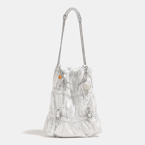 Slouchy lace-texture bucket bag with silver-tone chain strap, draped chain hardware, and shell charms, front view