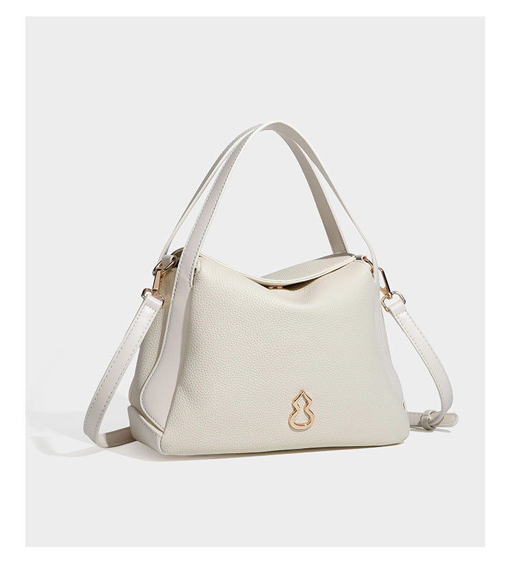 Structured pebbled leather-look shoulder bag with flap top, gold-tone emblem hardware, dual top handles, and detachable