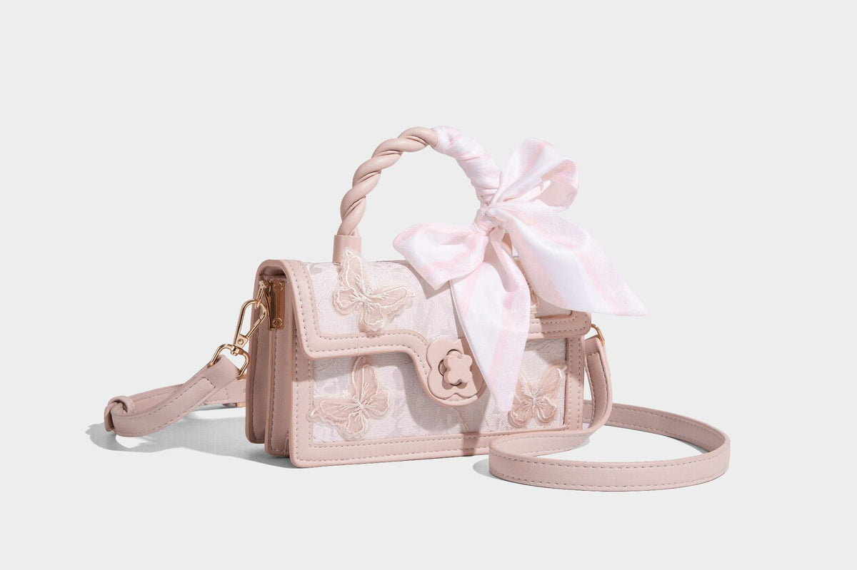 Small structured white flap bag with butterfly embroidery, flower-shaped turn-lock clasp, braided top handle with scarf bow