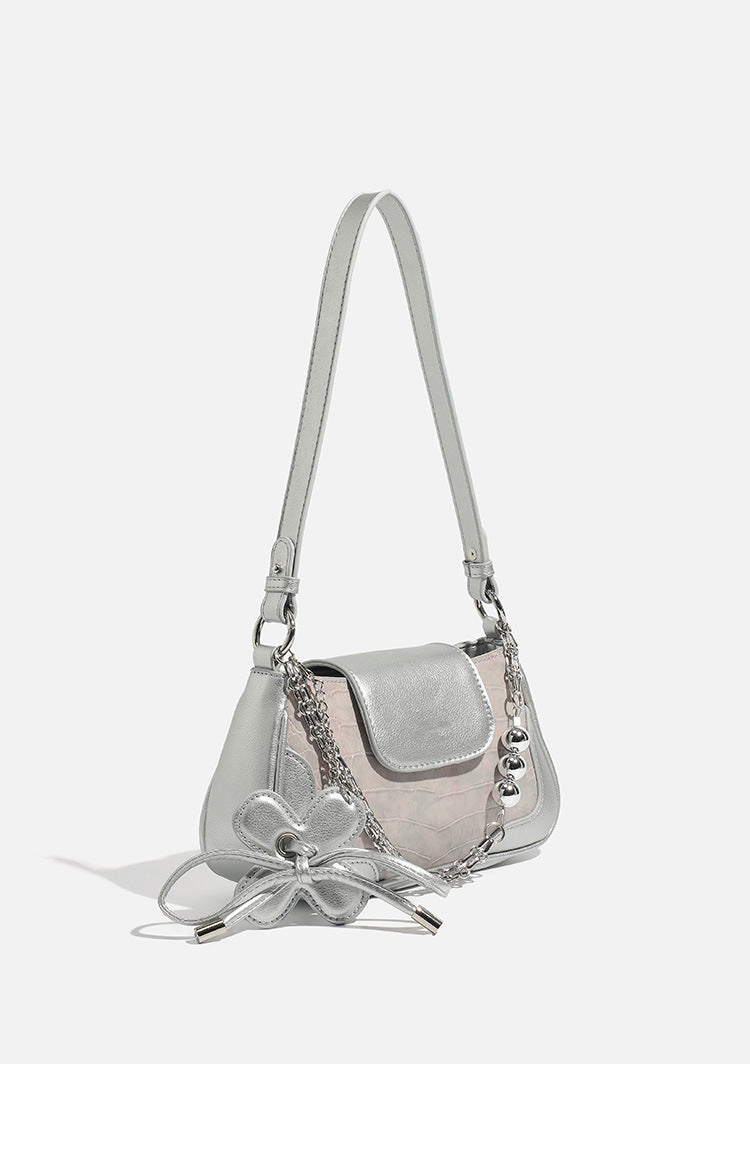 Compact silver flap shoulder bag with pale-pink crocodile-embossed panel, chain bead handle, bow charm, and adjustable