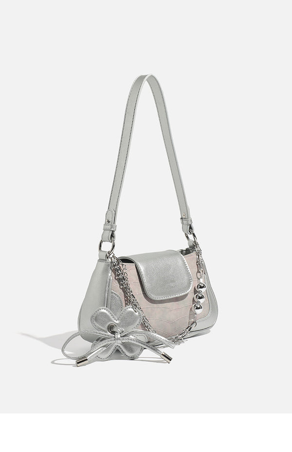 Compact silver flap shoulder bag with pale-pink crocodile-embossed panel, chain bead handle, bow charm, and adjustable