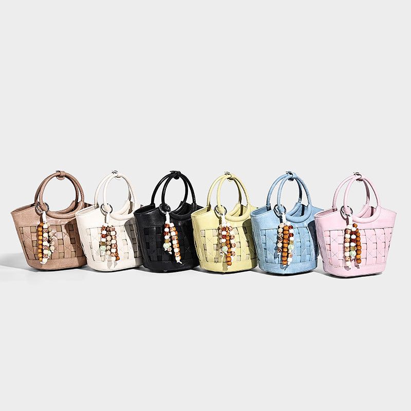 Small structured woven bucket bag with round top handle, beaded charm, and detachable shoulder strap in leather-look finish
