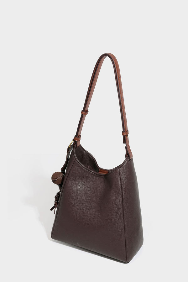 Hobo-Schultertasche in dunklem Espresso mit genarbter Oberfläche, warmen cognacfarbenen Details, verstellbarem schmalem Riemen, goldfarbenen Ringbeschlägen und geknotetem