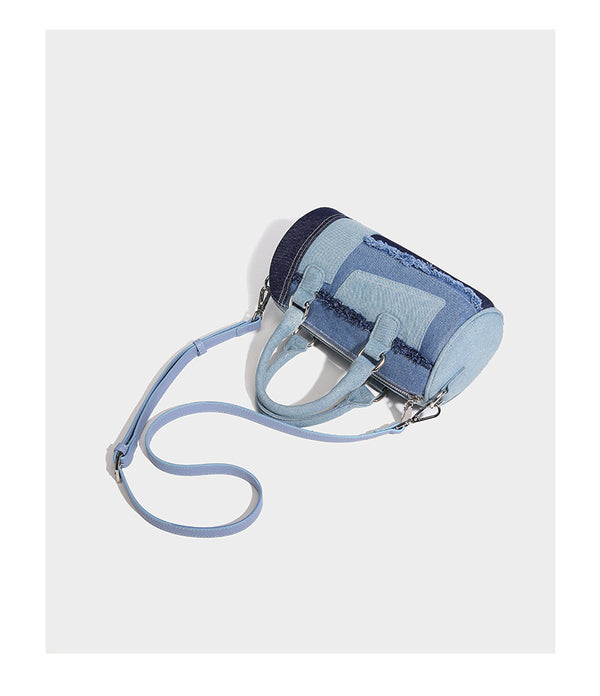 Mini barrel handbag in light and dark denim patchwork with frayed seam trim, dual top handles, top zip closure, and, detail