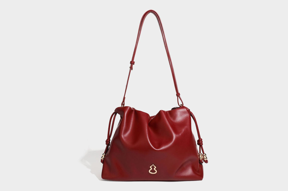 Slouchy ruched drawstring shoulder bag in smooth leather-look finish with gold-tone emblem and slim adjustable strap, detail