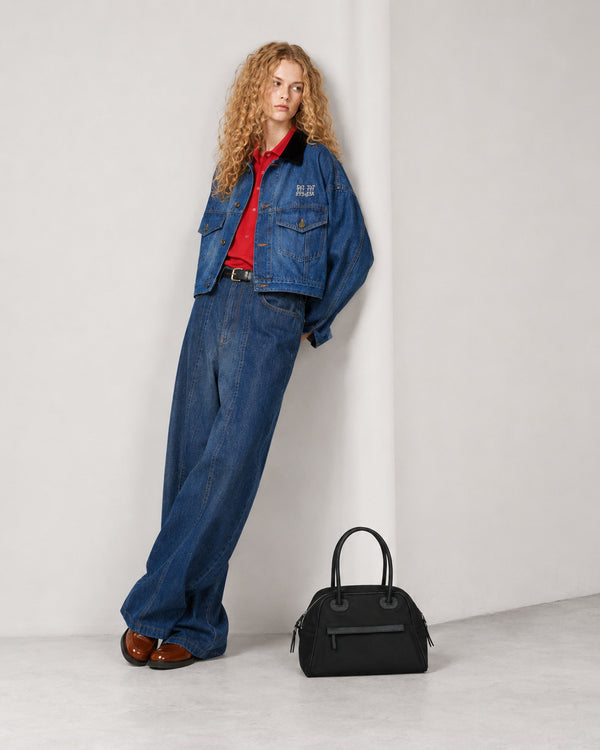 Structured dome top-handle bag in matte nylon with pebbled vegan leather-look trim, zip-top closure, front slip pocket, and