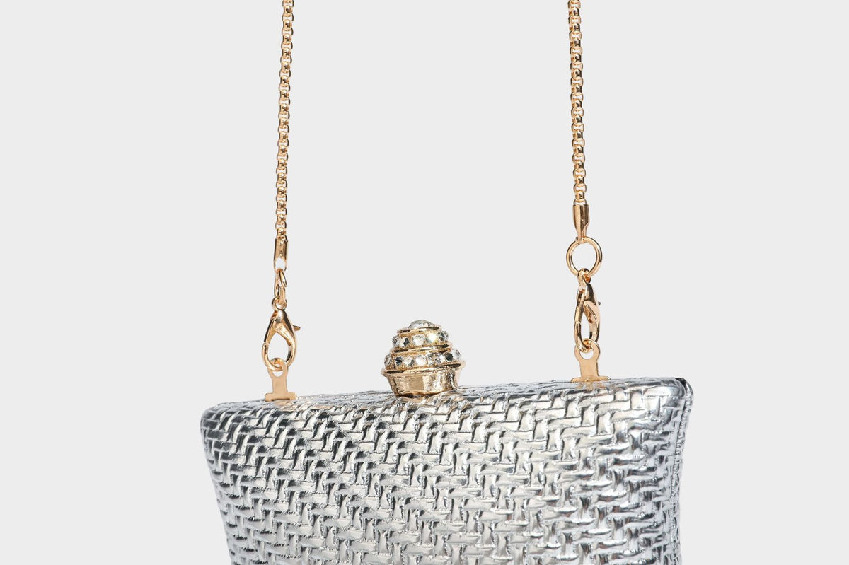 Small structured rectangular metallic woven-texture clutch bag with jeweled knob clasp and gold-tone chain strap, detail view