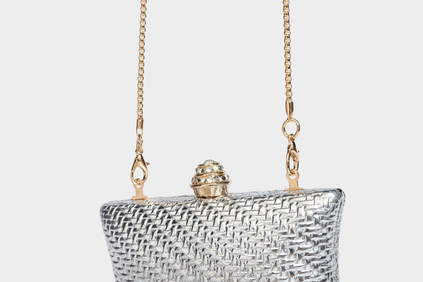 Small structured rectangular metallic woven-texture clutch bag with jeweled knob clasp and gold-tone chain strap, detail view