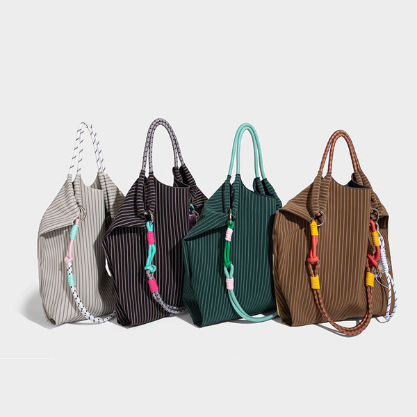 Slouchy pinstripe tote bag with braided rope handles, metal ring hardware, and colorful knotted rope charm, detail view 2