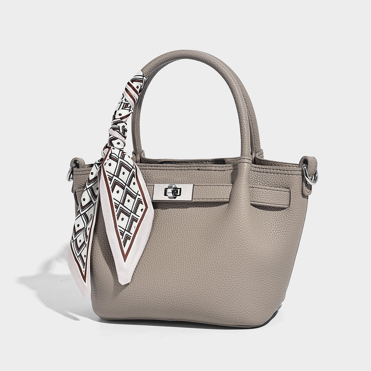 Kleine strukturierte Henkeltasche aus genarbtem Material in Taupe mit zwei Henkeln, bedrucktem Schalband, vorderem Drehverschluss und, Detailansicht