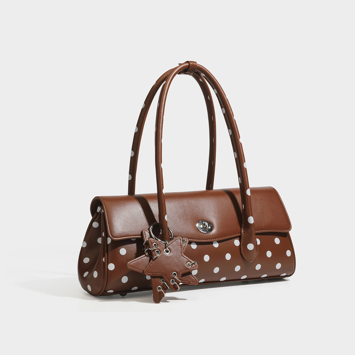 Structured polka-dot baguette bag with glossy leather-look finish, dual top handles, silver-tone turn-lock flap closure, and