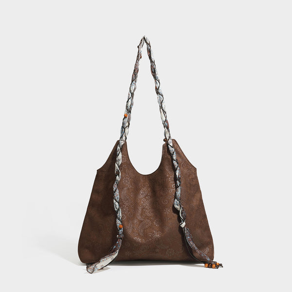 Slouchy paisley-embossed suede-look shoulder tote bag with braided patterned fabric straps and wood bead accents, detail view