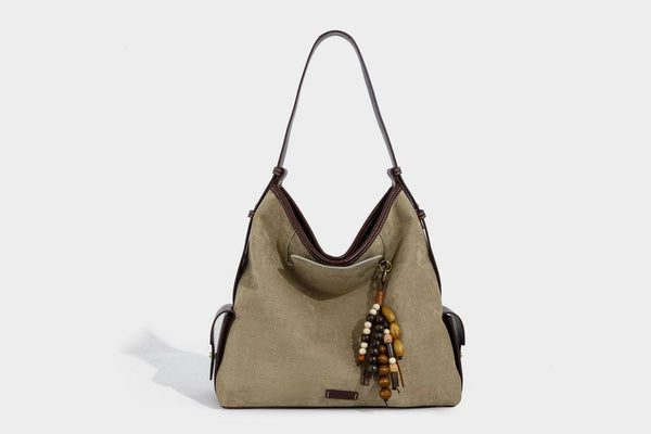 Weich fallende Hobo-Schultertasche in Khaki mit matter Velourslederoptik, Besatz in dunkelbrauner Lederoptik, Quastenanhänger mit Perlen und seitlicher Klappe, Detailansicht