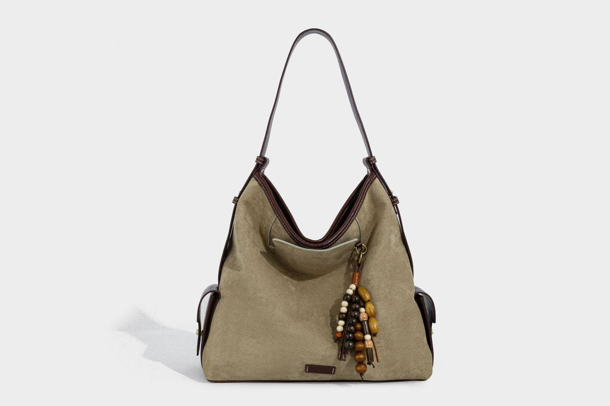 Lässig fallende Hobo-Schultertasche in Khaki aus mattem Material in Wildlederoptik mit dunkelbraunem Besatz in Lederoptik, Quastenanhänger mit Perlen und seitlicher Klappe, Detailansicht