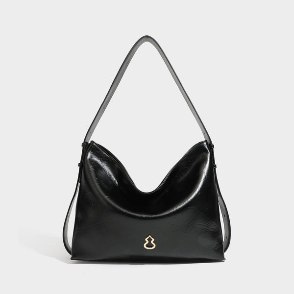 Lässig-sackförmige Hobo-Schultertasche mit offenem oberen Rand in glänzender karamellfarbener Lederoptik, goldfarbenen Logo-Beschlägen und langem verstellbarem