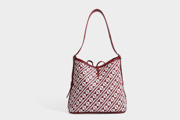 Woven geometric bucket shoulder bag in white and dark brown two-tone pattern with leather-look trim and drawstring top