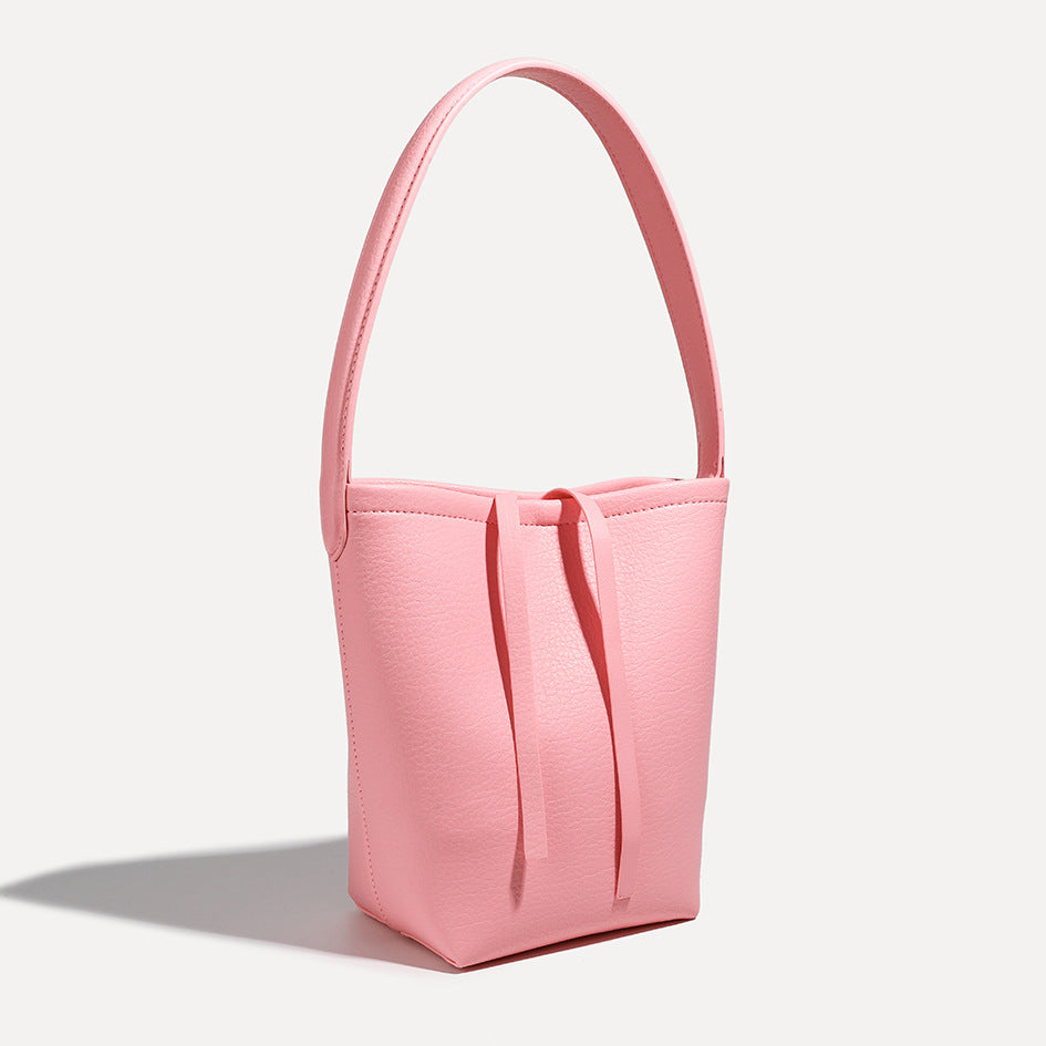 Mini tapered bucket bag in pebbled leather-look finish with front tie straps and single shoulder strap, detail view 3