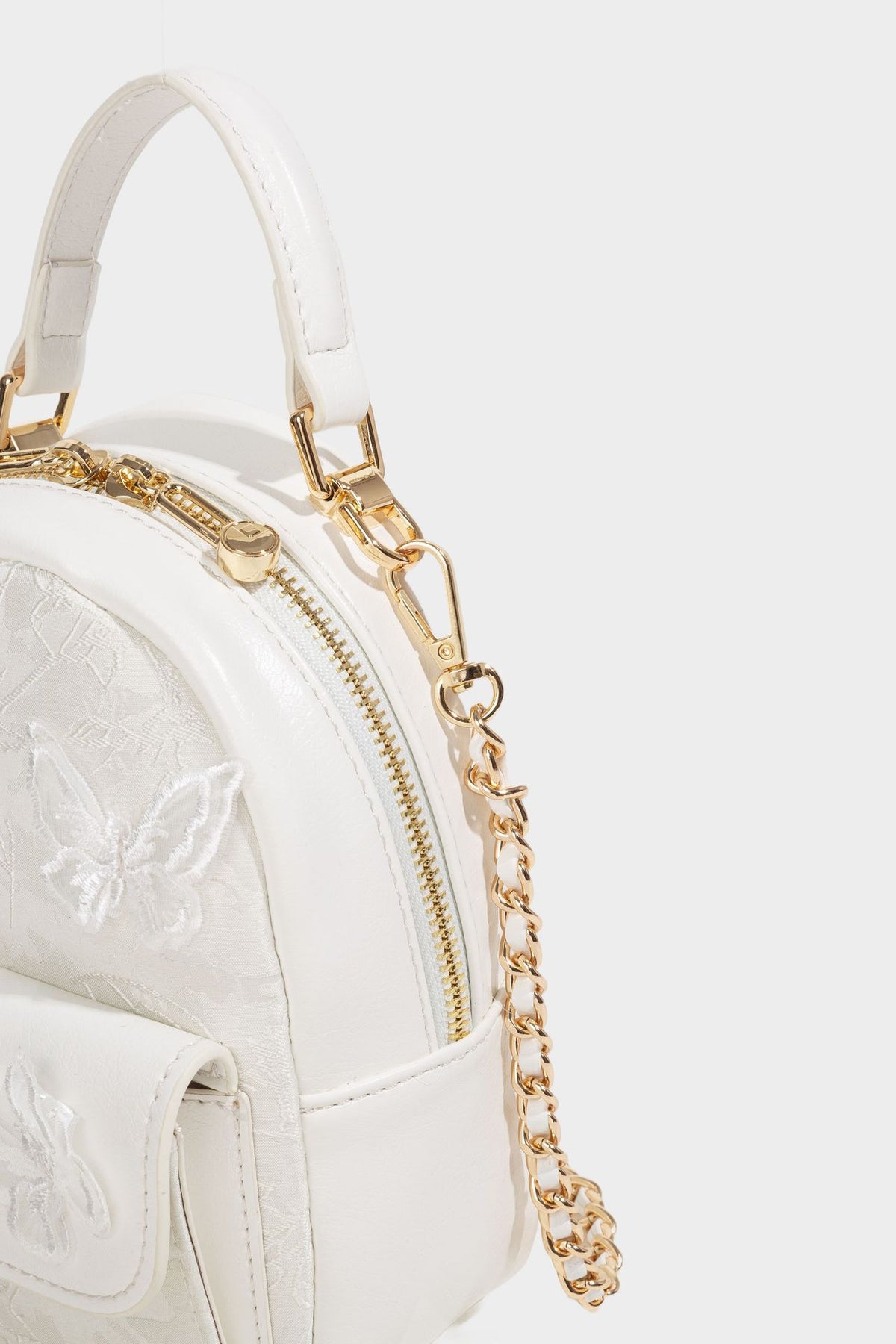 Structured mini backpack handbag with butterfly embroidery, gold-tone chain strap, and turn-lock front flap pocket, detail