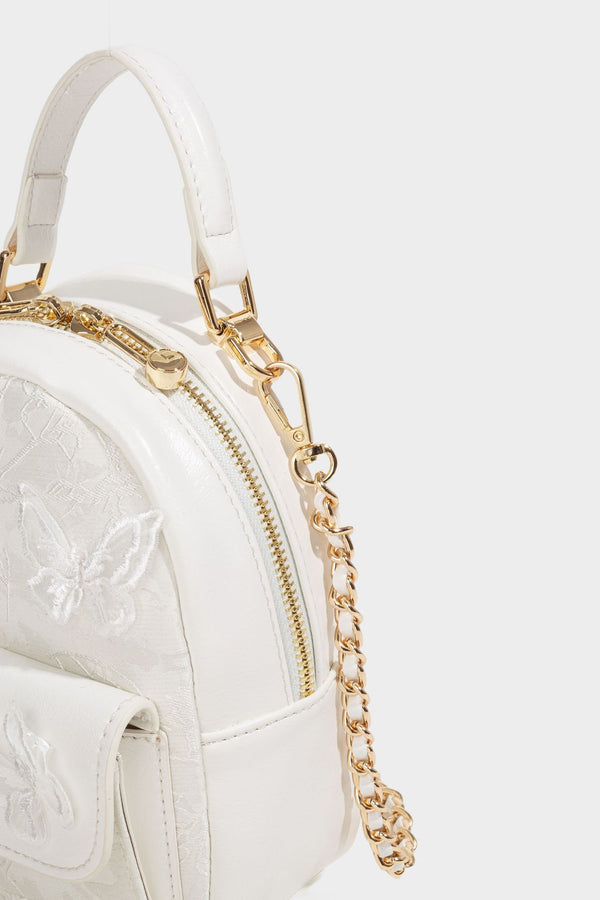 Structured mini backpack handbag with butterfly embroidery, gold-tone chain strap, and turn-lock front flap pocket, detail