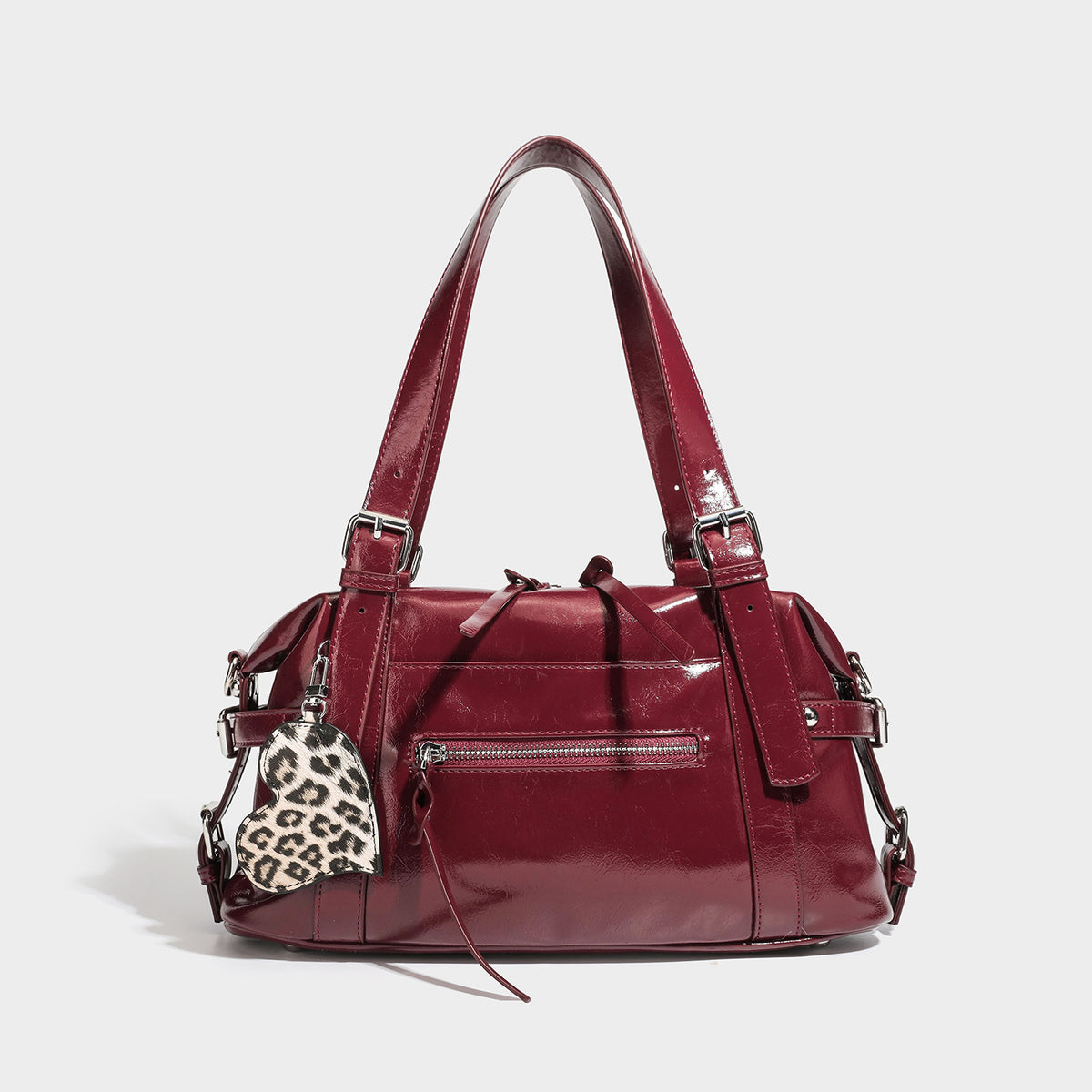 Structured glossy leather-look shoulder bag with rounded body, silver-tone hardware, front zip pocket, and leopard-print