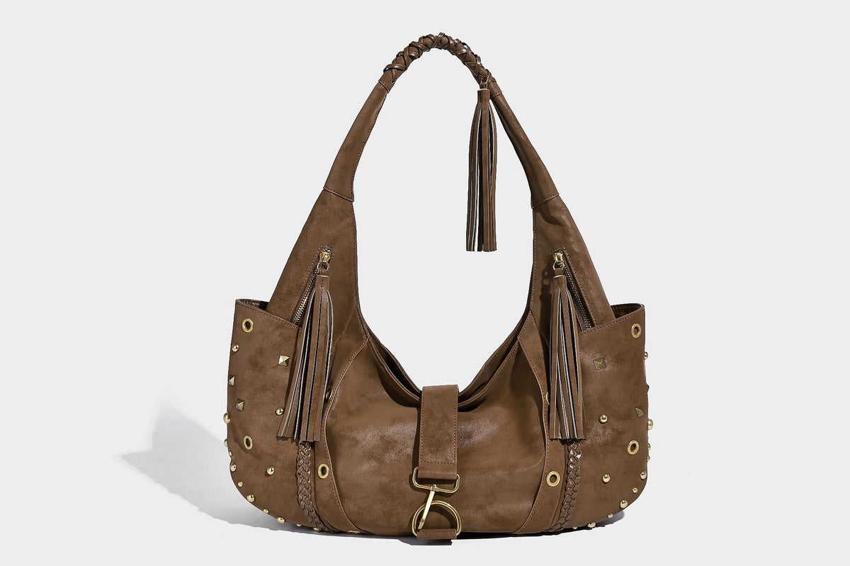 Slouchy crescent hobo bag in matte brown suede-like finish with gold-tone studs, grommets, braided top handle, tassel side