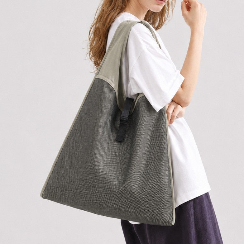 Oversized triangular mesh tote bag with matte olive-khaki fabric straps and trim, dark open-weave mesh body, matte black